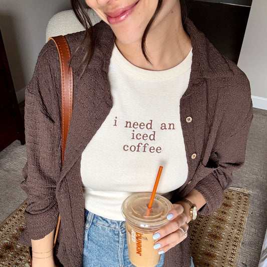 woman wearing a natural women's cropped micro rib tank top with custom i need an iced coffee embroidered design