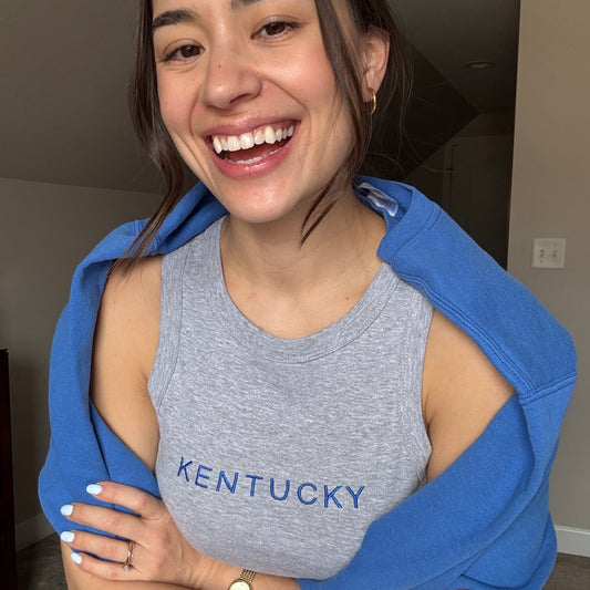 woman wearing a cropped micro rib racer tank top with custom KENTUCKY embroidered design across the chest in royal blue thread