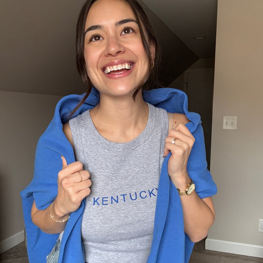 woman wearing a cropped micro rib racer tank top with custom KENTUCKY embroidered design across the chest in royal blue thread
