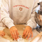 woman making cookies wearing a gray sweatshirt with 'in my baking era' and a gingerbread cookie embroidered across the chest