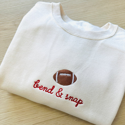 sweet cream sweatshirt with an embroidered football icon and "bend & snap" in a script font