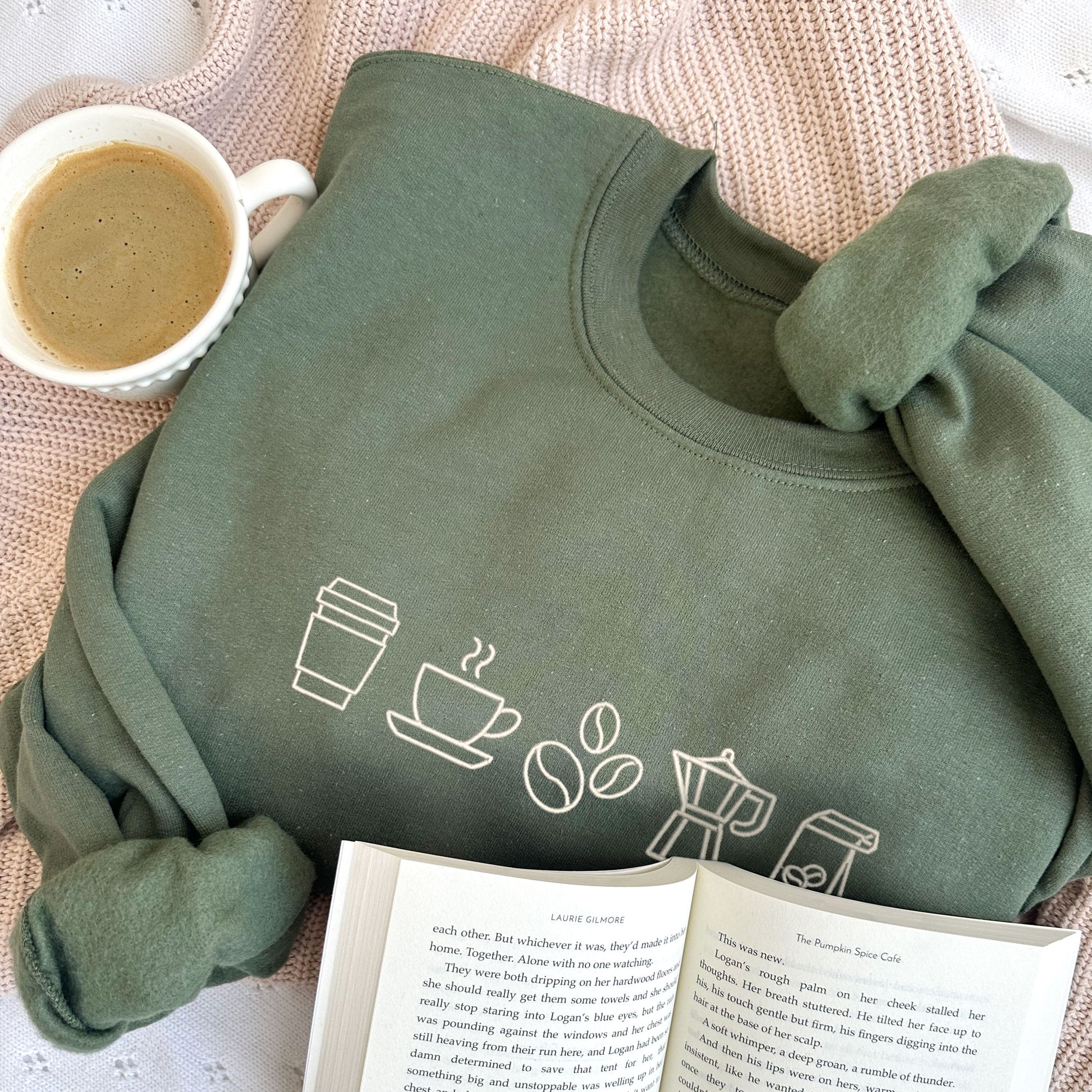 styled flat lay of a military green crewneck sweatshirt with embroidered coffee icons across the chest in natural thread
