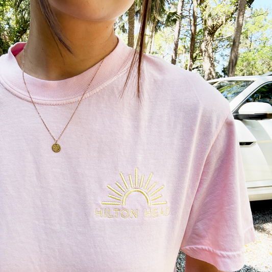 close up of a girl wearing a blossom comfort colors t-shirt with custom embroidery of a sun and hilton head, sc on the left chest in butter thread