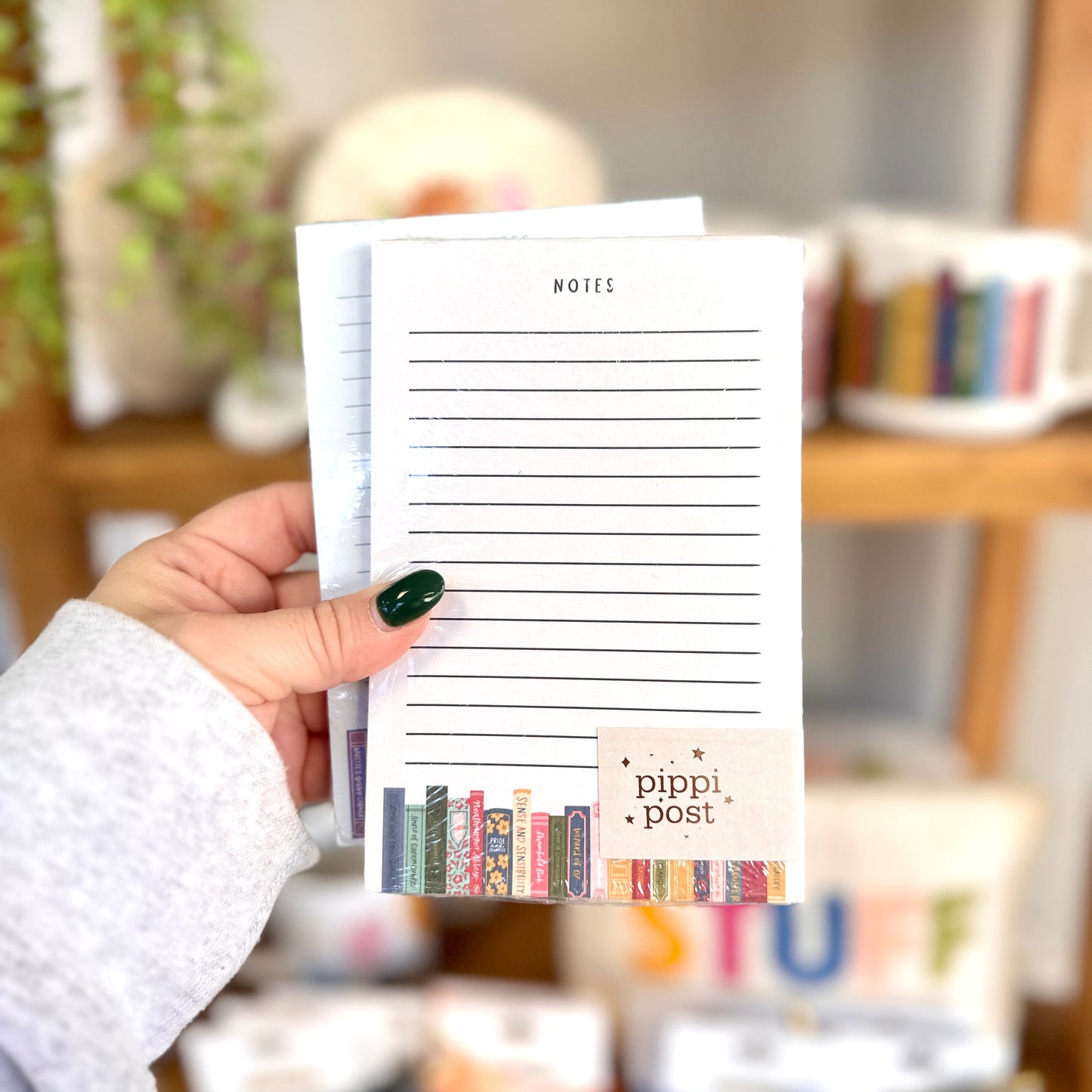Hand holding a notepad with 'pippi post' branding in a blurred indoor setting