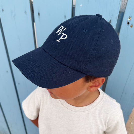 little boy wearing a navy baseball hat with mini embroidered staggered initial