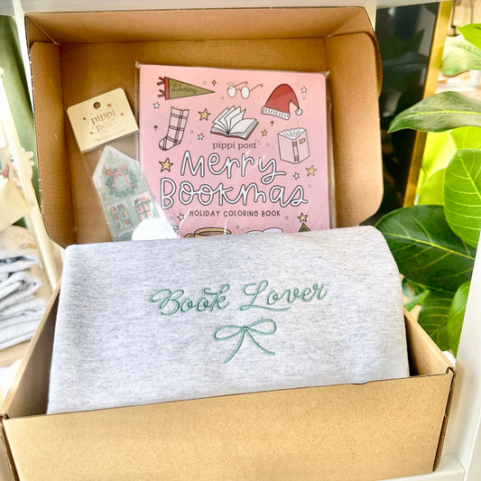 Box containing a 'Merry Bookmas' coloring book and bookmark and a sweatshirt with 'Book Lover' embroidery.