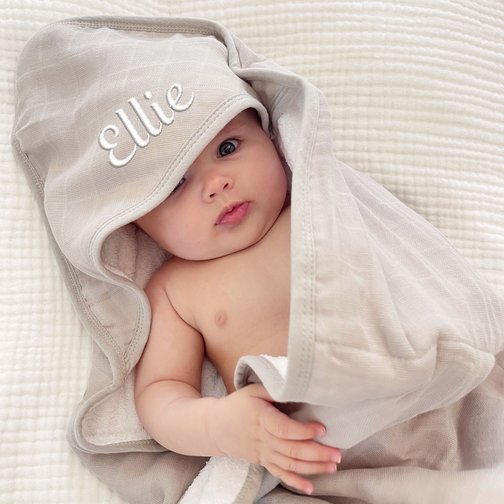 baby wrapped in a porpoise gray plaid hooded bath towel with name embroidered on the hood in a white thread