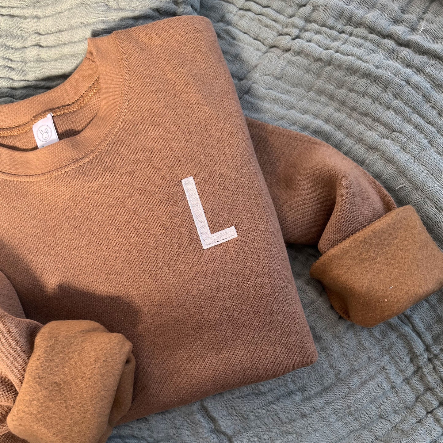 coyote brown toddler crew with a single block initial embroidered on the left chest in camel thread.
