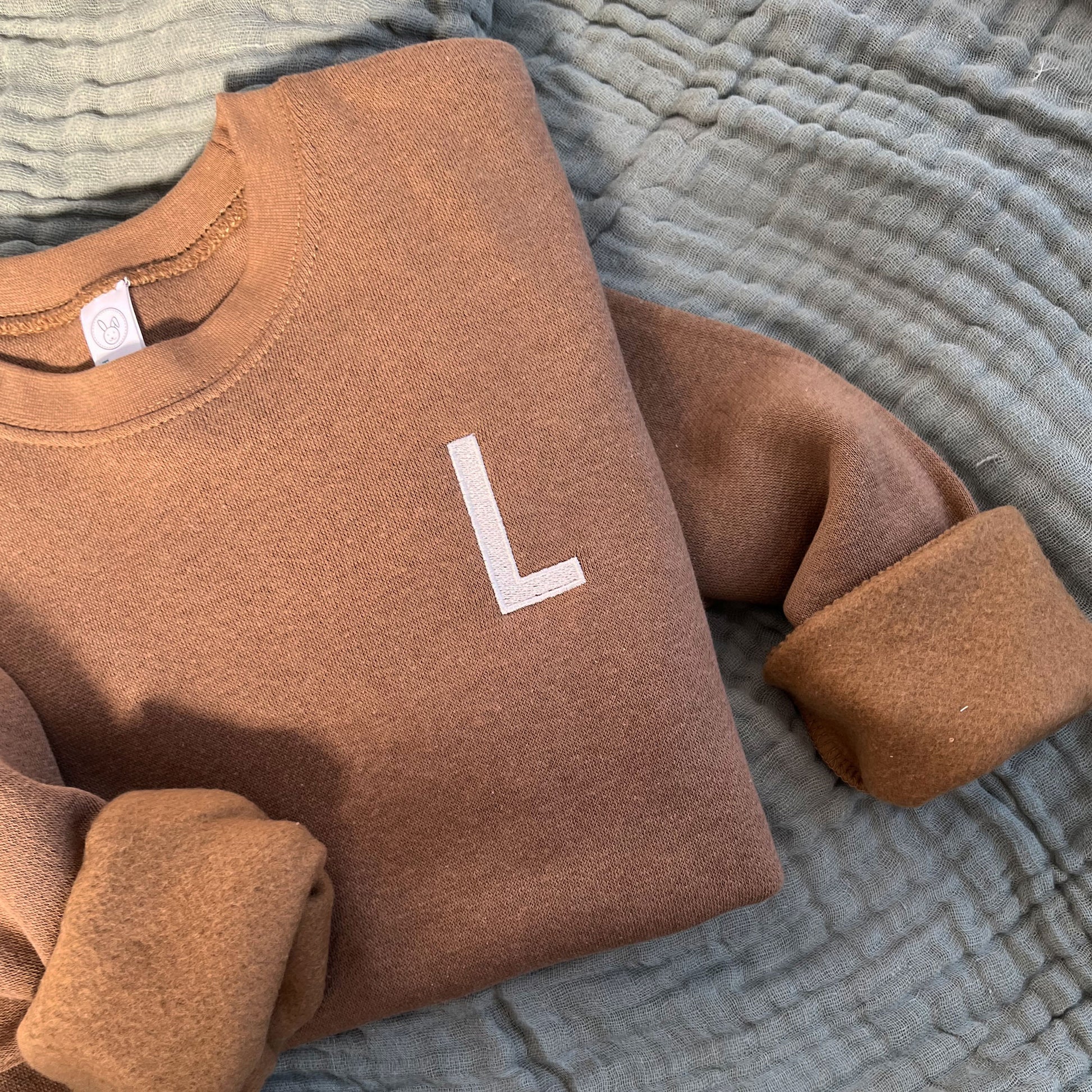 coyote brown toddler crew with a single block initial embroidered on the left chest in camel thread.