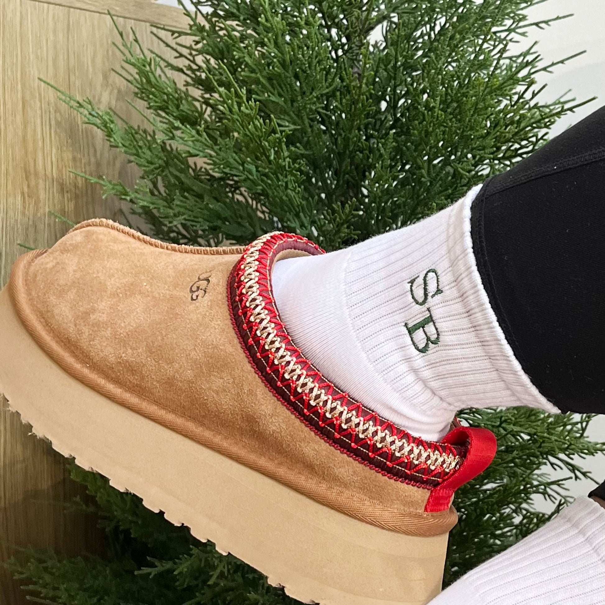 Woman wearing platform Ugg slides and white midi crew socks with custom embroidered staggered initials in Ivy green thread.