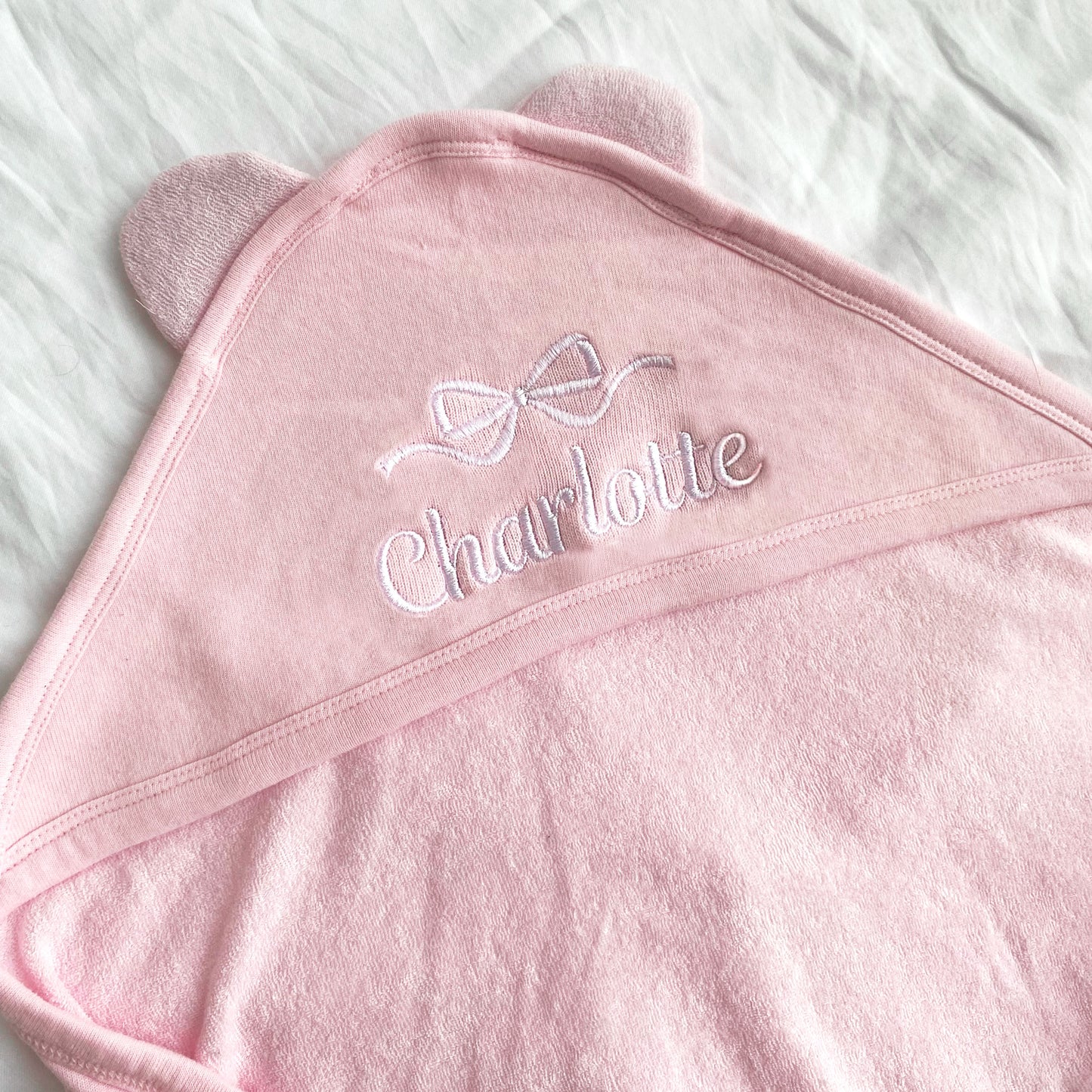 Full name and bow embroidered hooded baby towel on pink with White thread