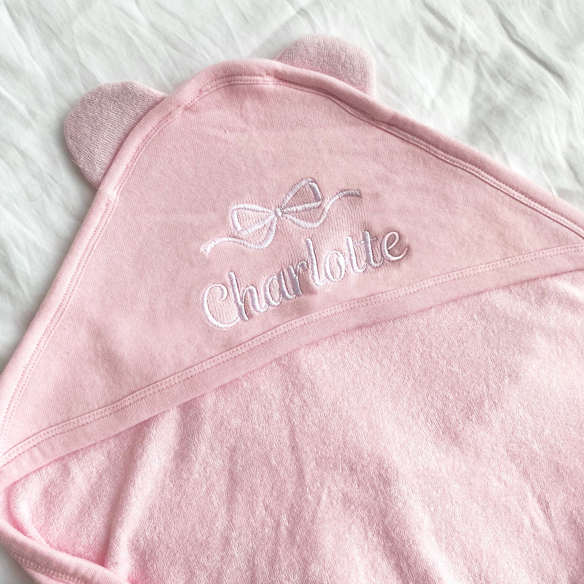Full name and bow embroidered hooded baby towel on pink with White thread