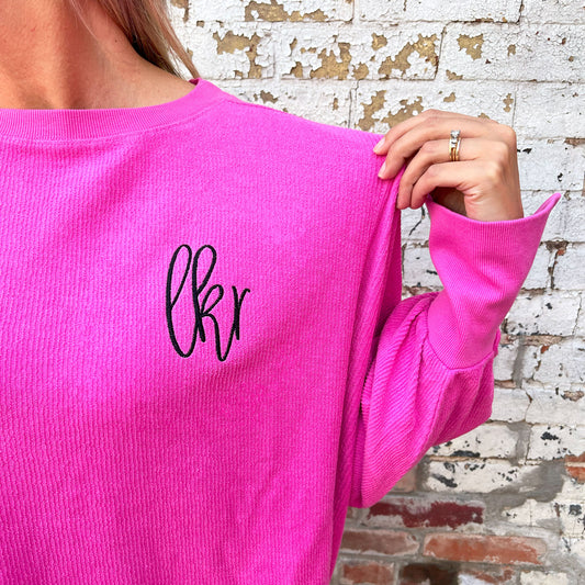 close up of an embroidered monogram on a ribbed pinkberry crewneck sweatshirt