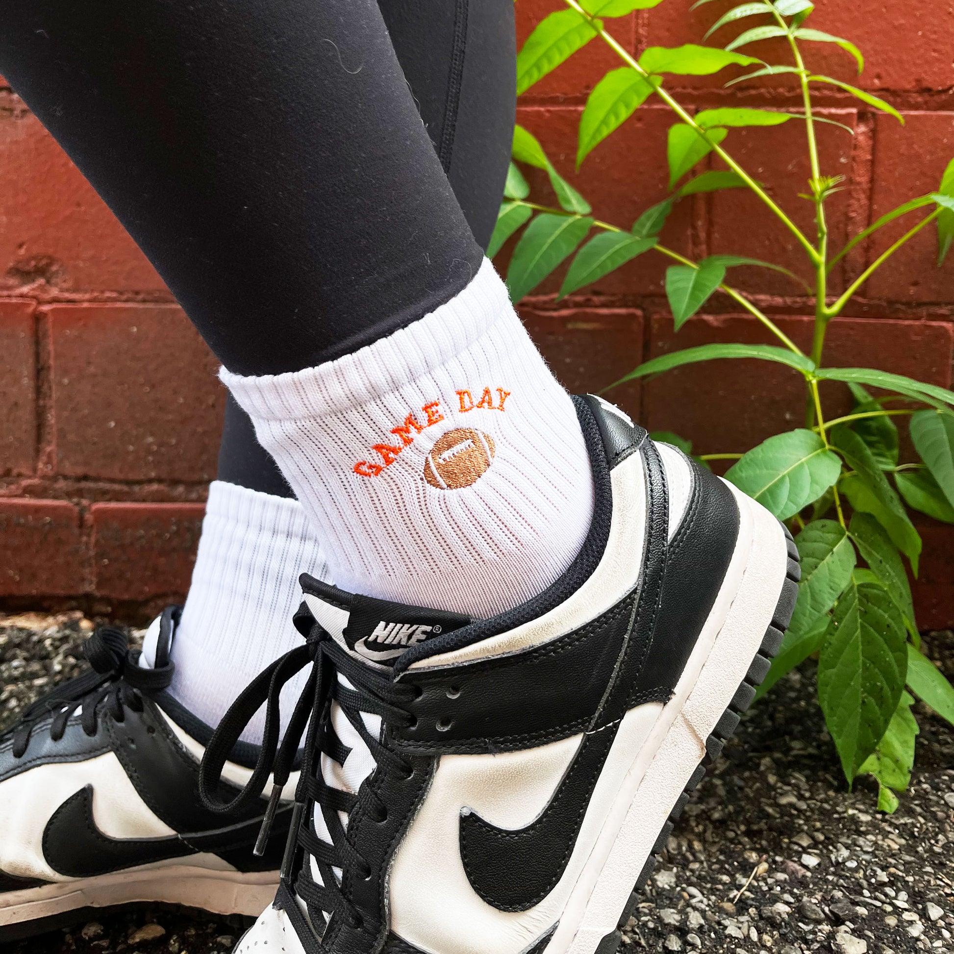 woman wearing black and white Nike shoes and ankle crew socks with custom embroidered football game day design
