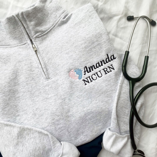 ash grey quarter zip sweatshirt with a custom name, credential, and baby feet embroidered design on the left chest