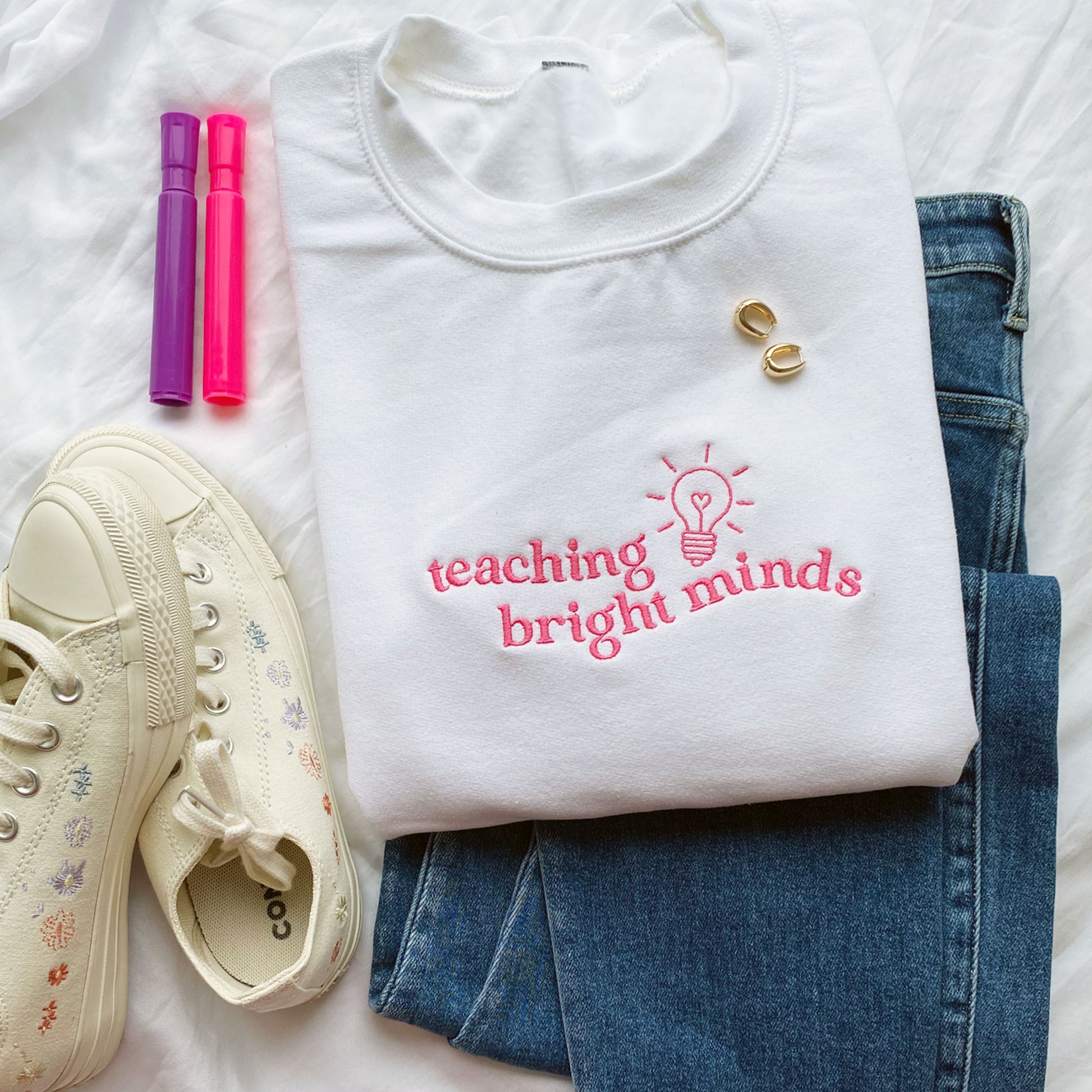 white teacher pullover sweatshirt with a teaching bright minds lightbulb embroidered design on the chest