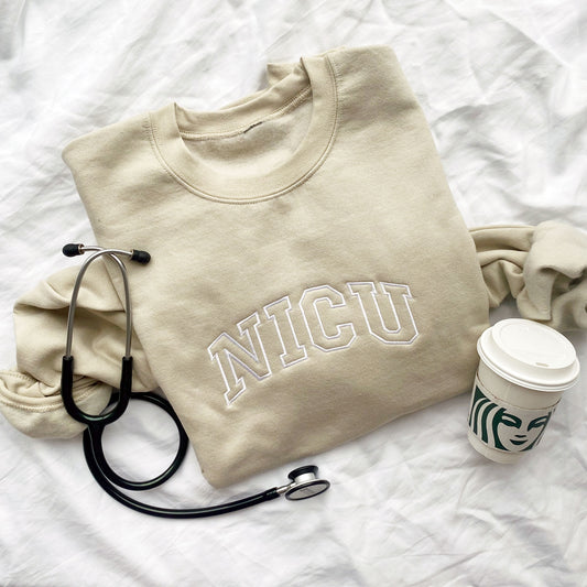 nurse crewneck sweatshirt in sand with nicu embroidered across the chest in an arched athletic block font.