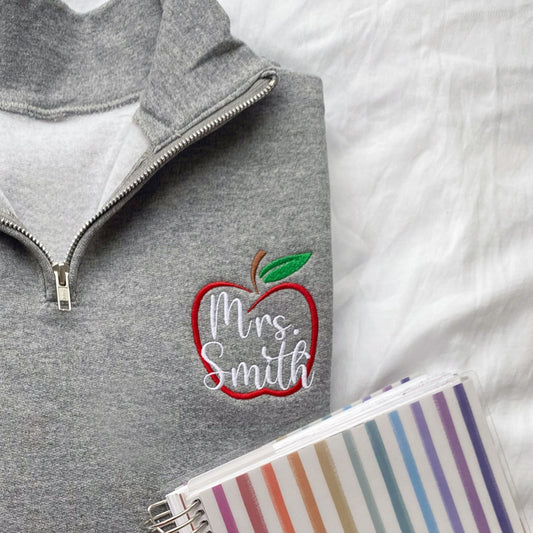 teacher quarter zip embroidered with a personalized name and outlined apple design