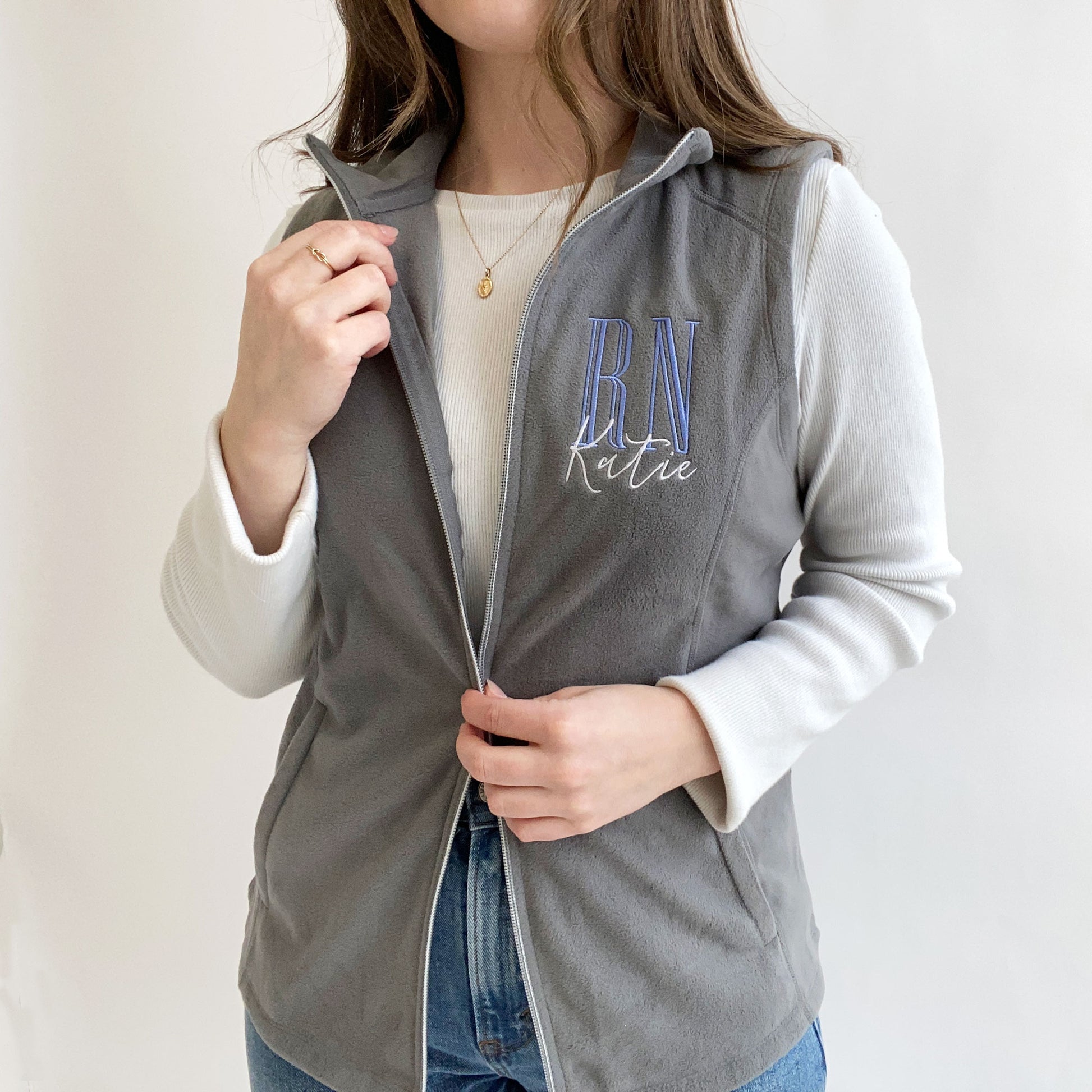 young woman modeling a grey fleece nurse vest with personalized RN design on the left chest