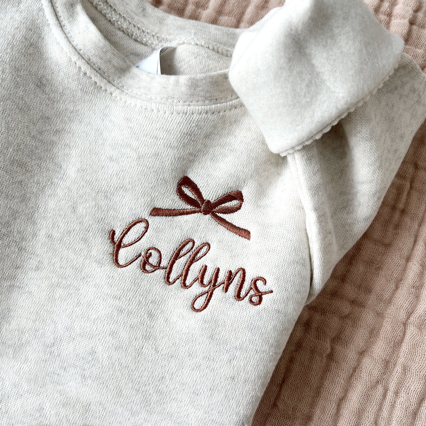 natural heather youth crewneck sweatshirt with embroidered bow and name design on the left chest in chestnut thread