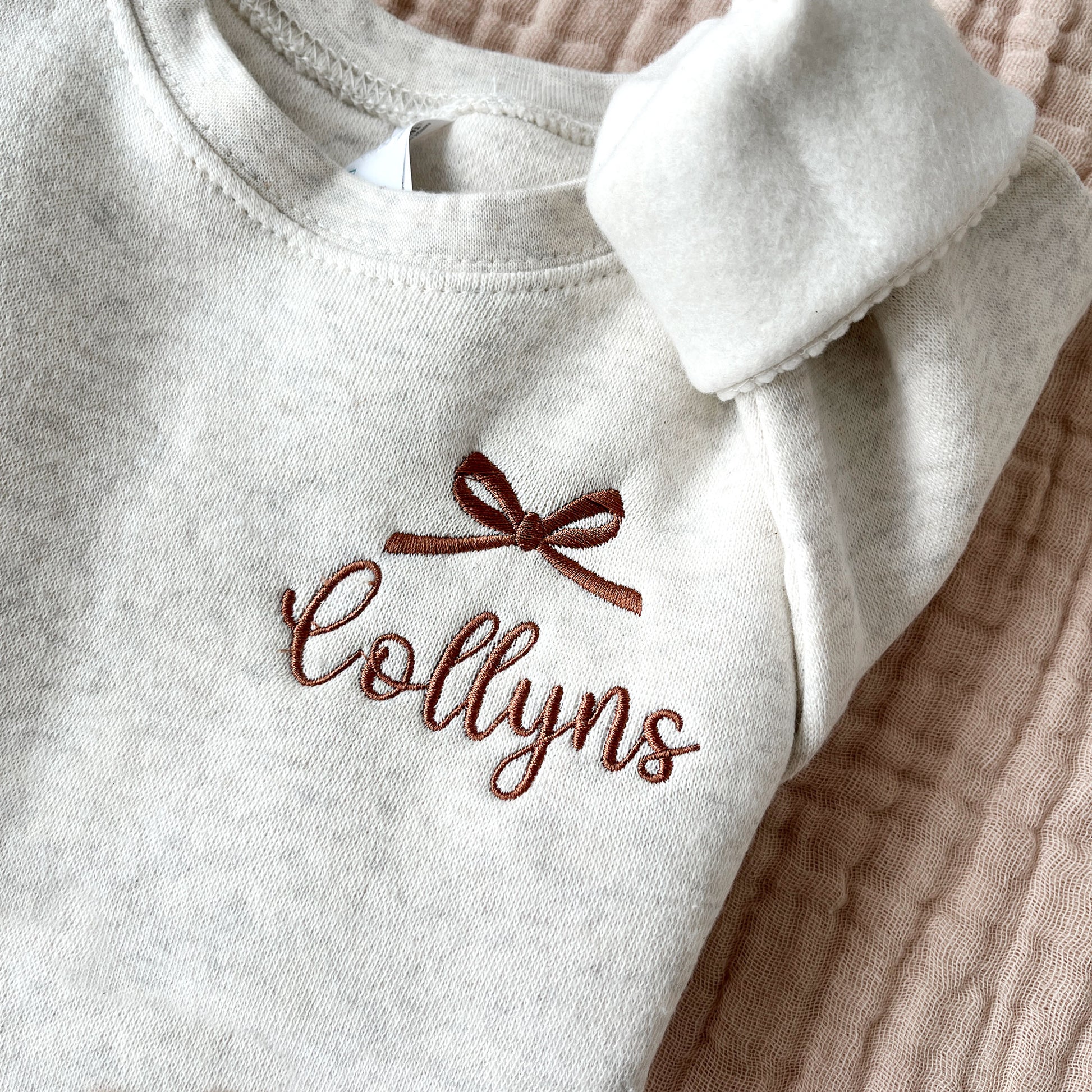 natural heather youth crewneck sweatshirt with embroidered bow and name design on the left chest in chestnut thread