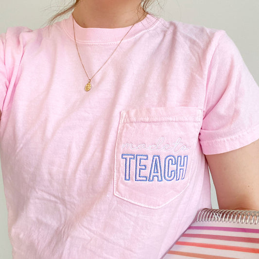 close up photo of a  young woman wearing a blossom comfort colors t-shirt with made to teach embroidered design on the pocket in white and periwinkle threads