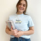 young woman modeling a chambray comfort colors tshirt with embroidered progress over perfection and pencil design