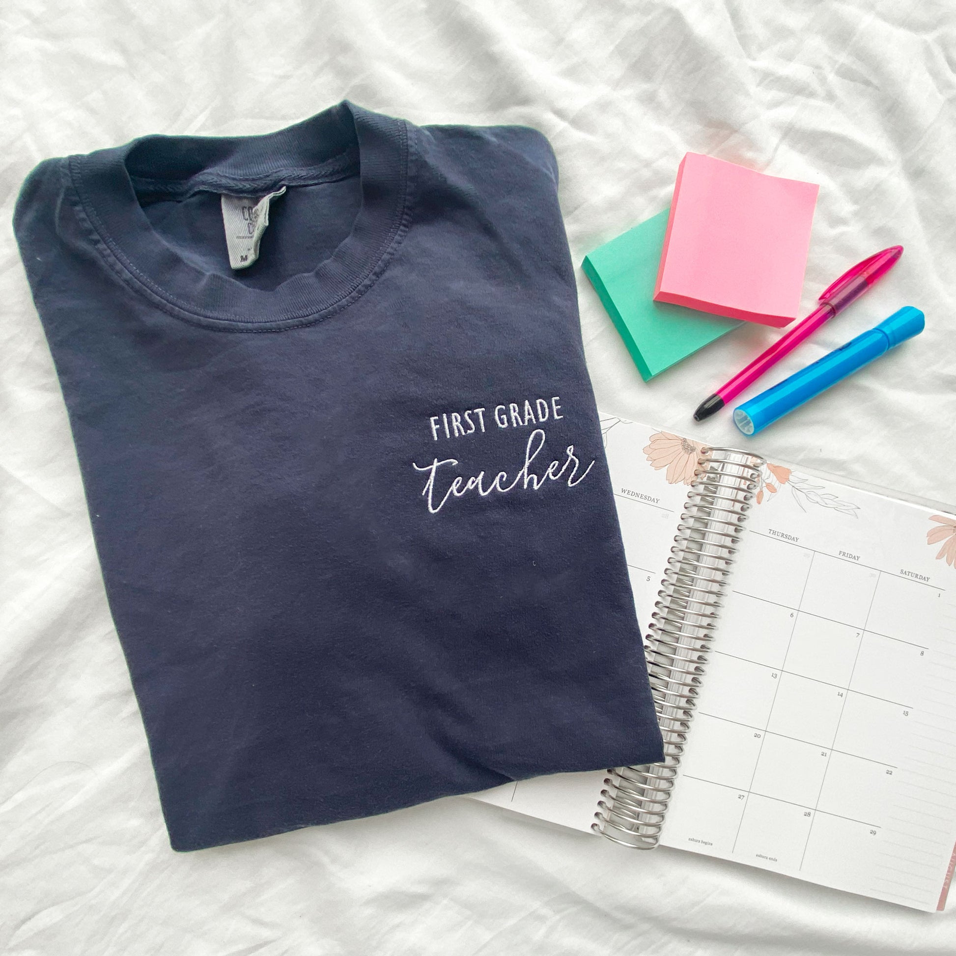 navy comfort colors tshirt with personalized grade level and teacher embroidered design in white thread styled with school supplies