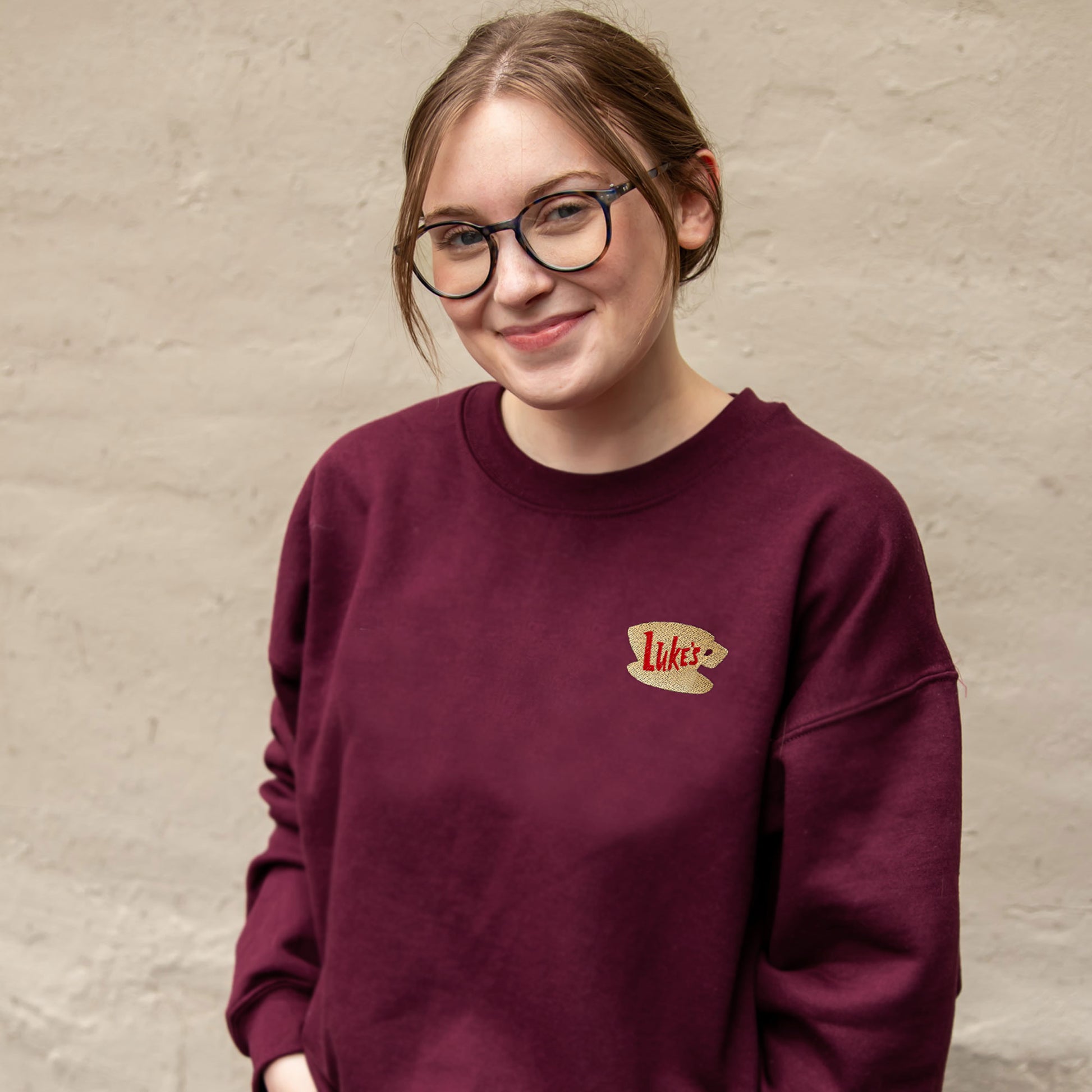 woman wearing a maroon sweatshirt with a Luke's diner embroidered logo