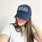 woman wearing a navy blue cap with an open block embroidered mama design