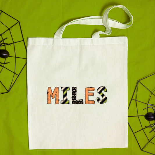 Natural tote bag with a fun custom name print in a mixed halloween inspired pattern text.