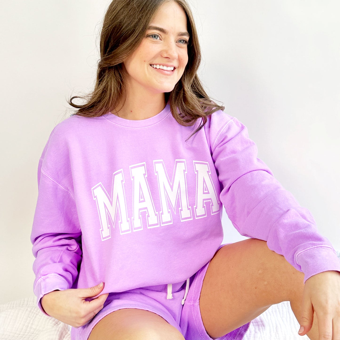 woman wearing a long sleeve top and short set in a bright violet color with a white large mama print across the chest