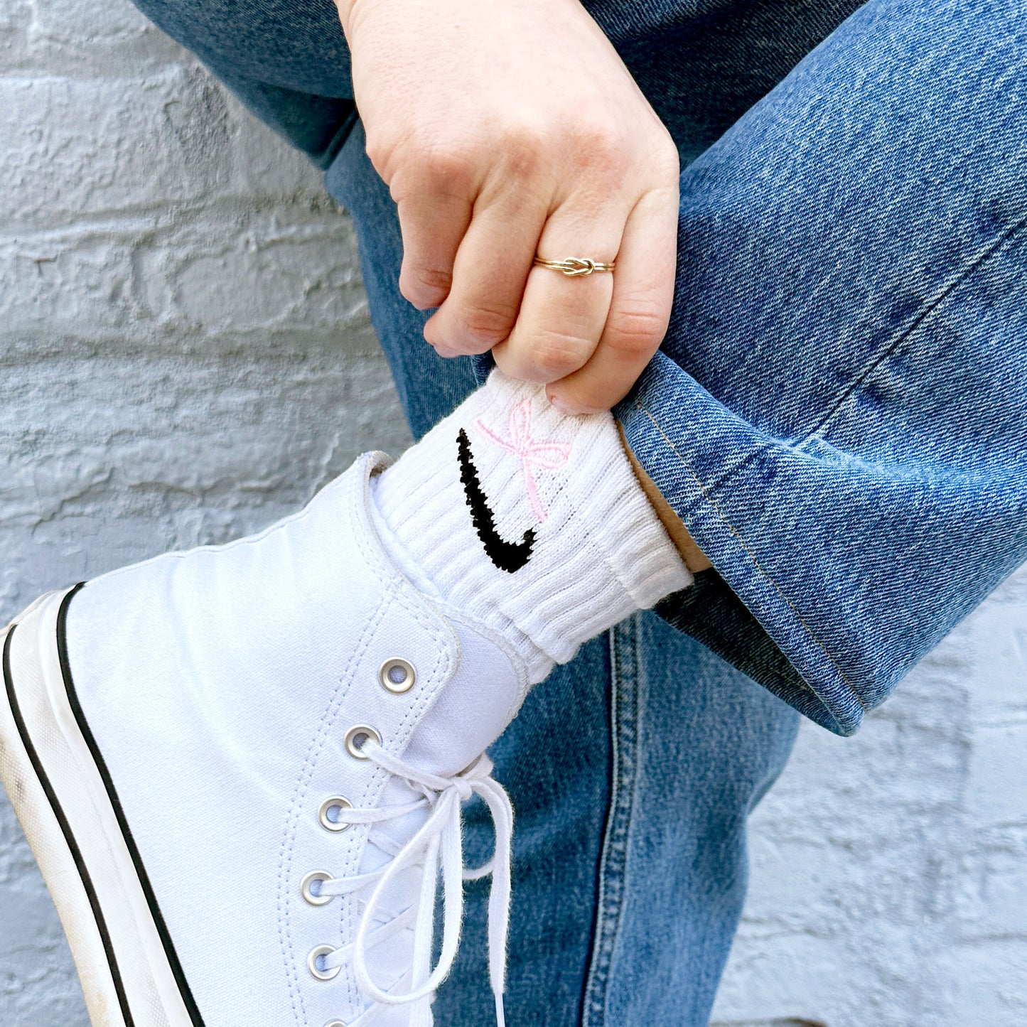 girl wearing high top sneakers with Nike socks peeking out featuring a mini light pink bow embroidered design