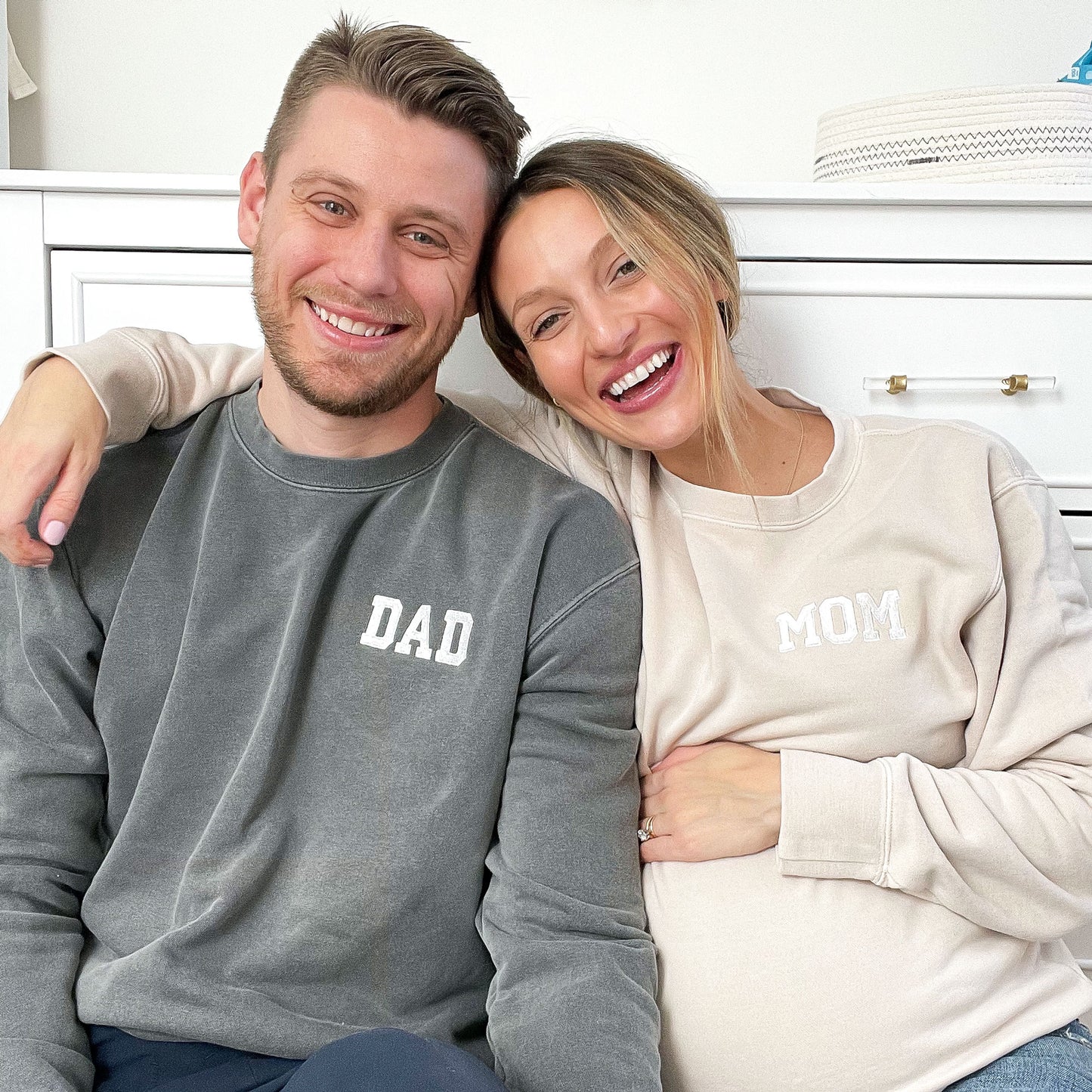 Man and woman wearing dad and mom embroidered crewneck sweatshirts