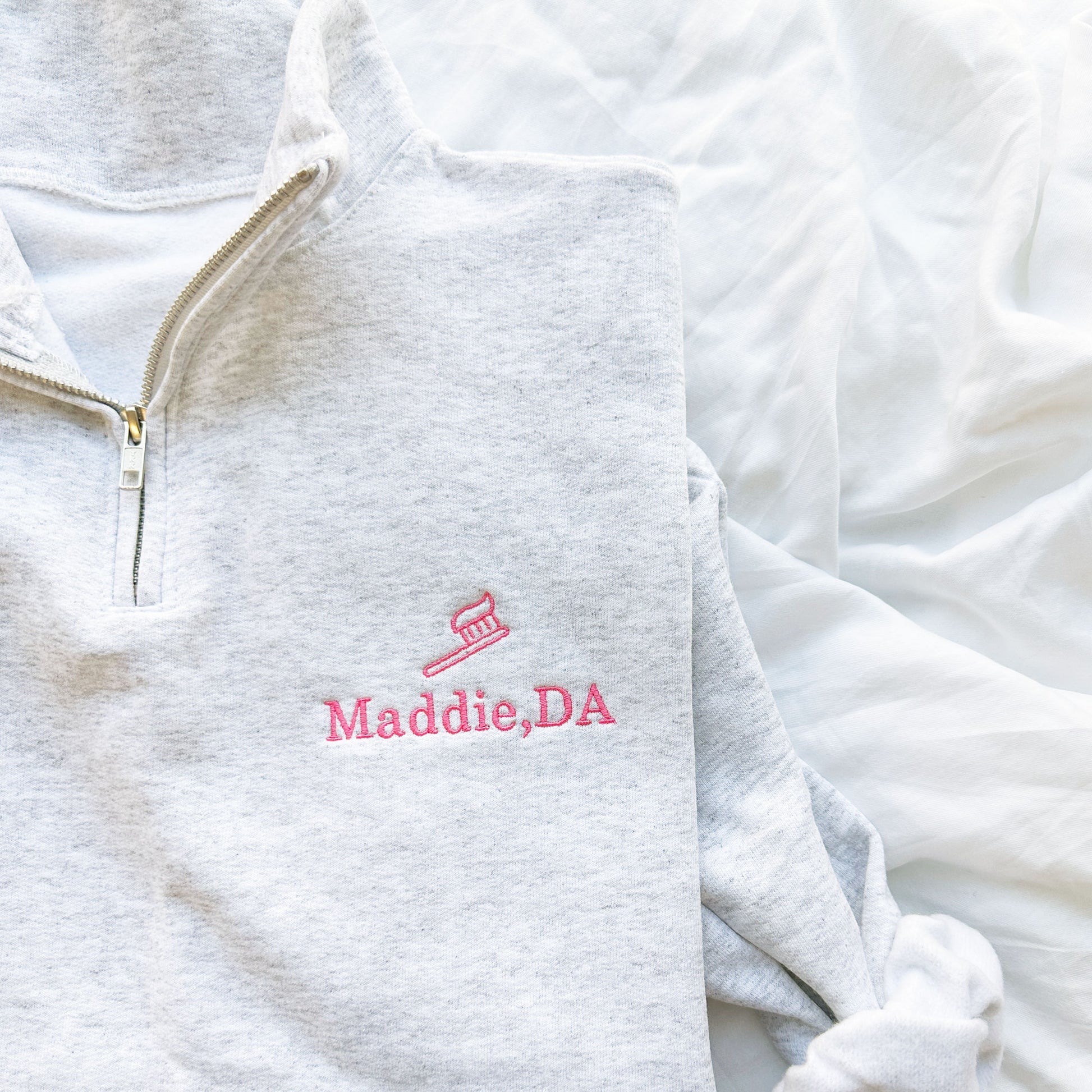 ash quarterzip sweatshirt with pink embroidered tooth brush and name Maddie, DA on the left chest