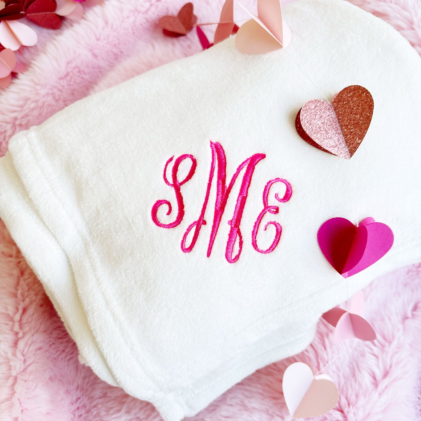 White blanket with SME monogram embroidered in pink