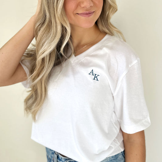 Close up of white vneck tshirt with mini AK staggered emeboidered initials in french blue thread