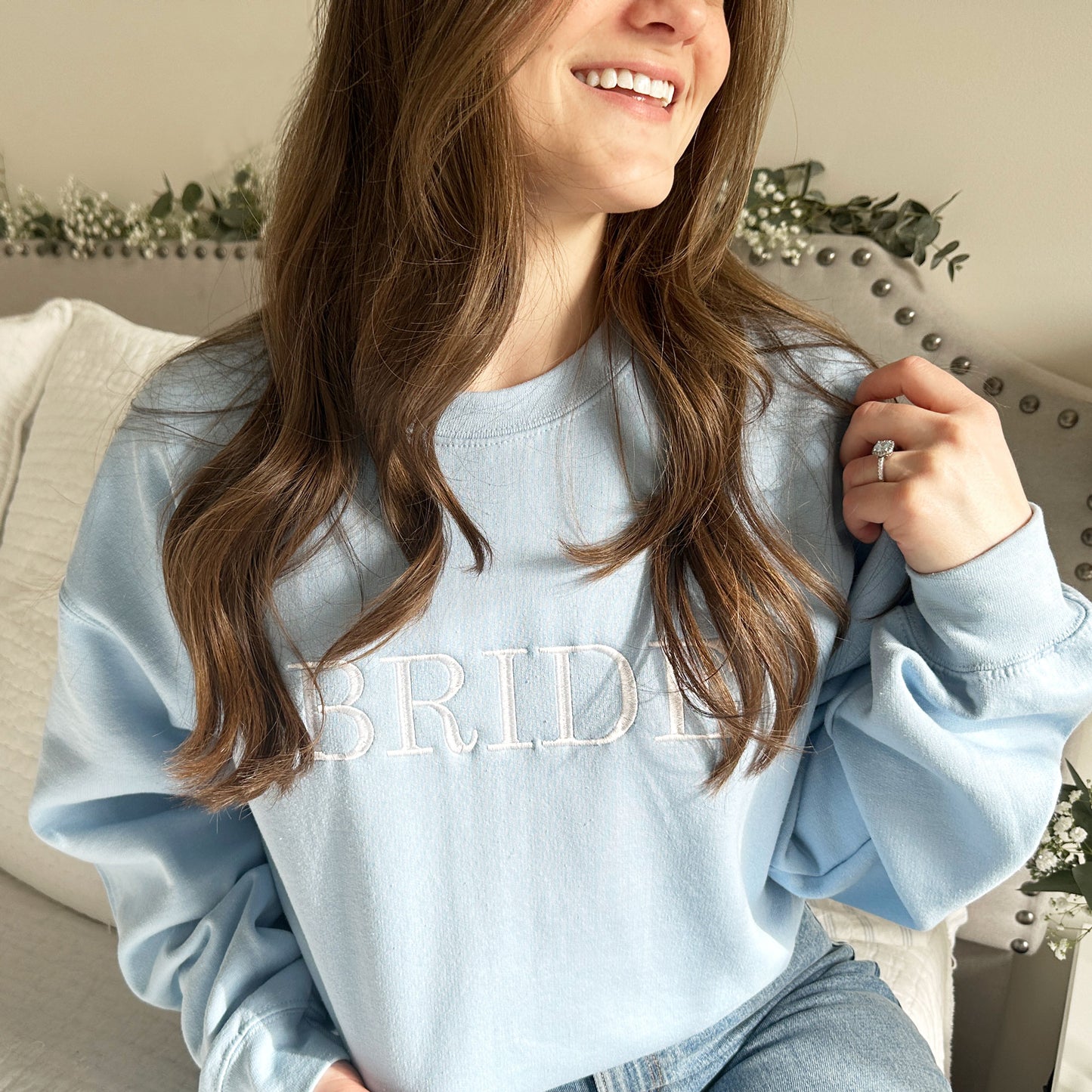 light blue crewneck sweatshirt with embroidered bride in white thread