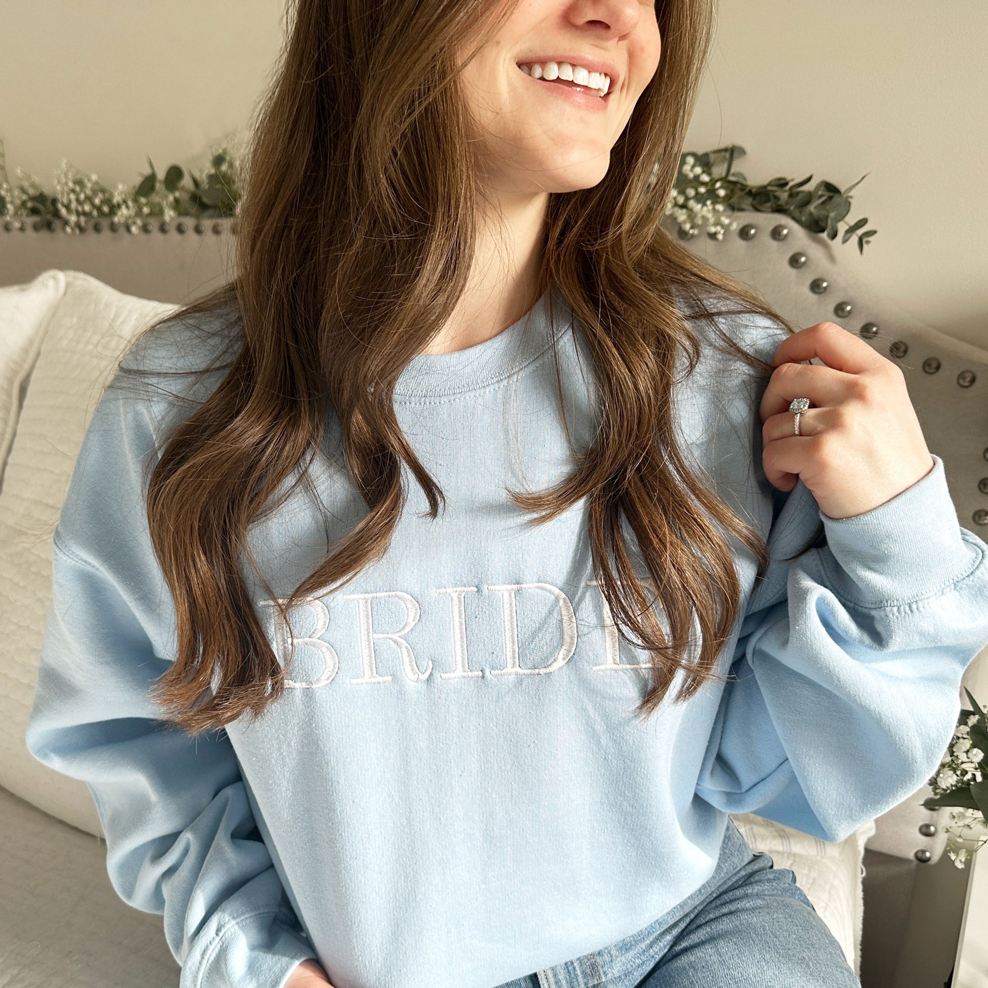 light blue crewneck sweatshirt with embroidered bride in white thread