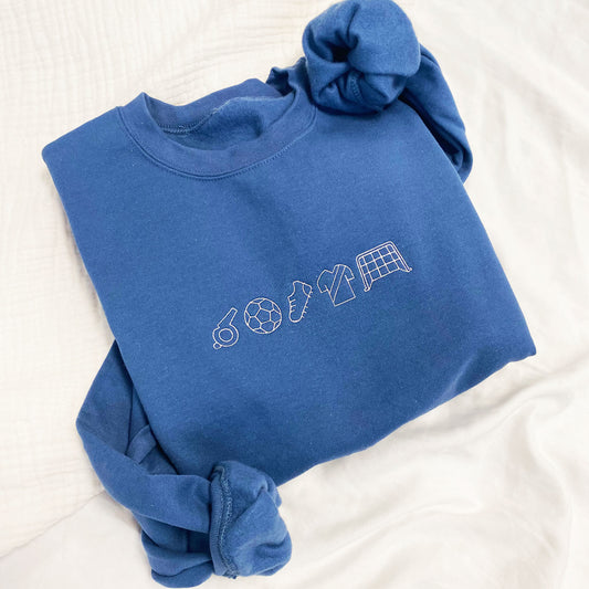 Close up of embroidered indigo crewnec sweatshirt with soccer icons in white thread