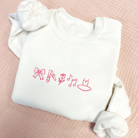 White crewneck sweatshirt with pink embroidered dance icons across the chest