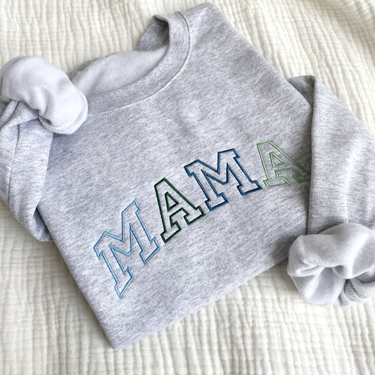 flat lay photo of an ash crewneck sweatshirt with large embroidered athletic block MAMA in alternating blues and greens
