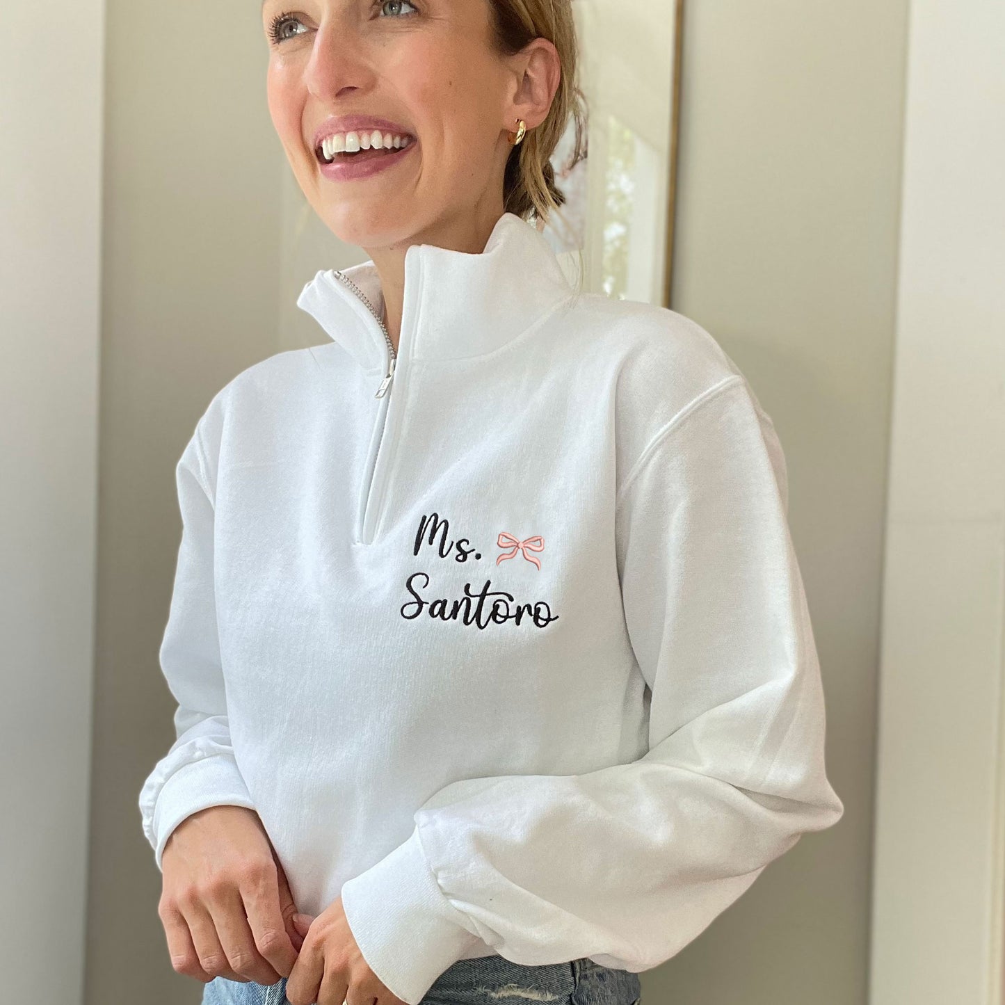 Kaylyn is wearing a white q-zip with embroidered name and mini coral pink embroidered bow