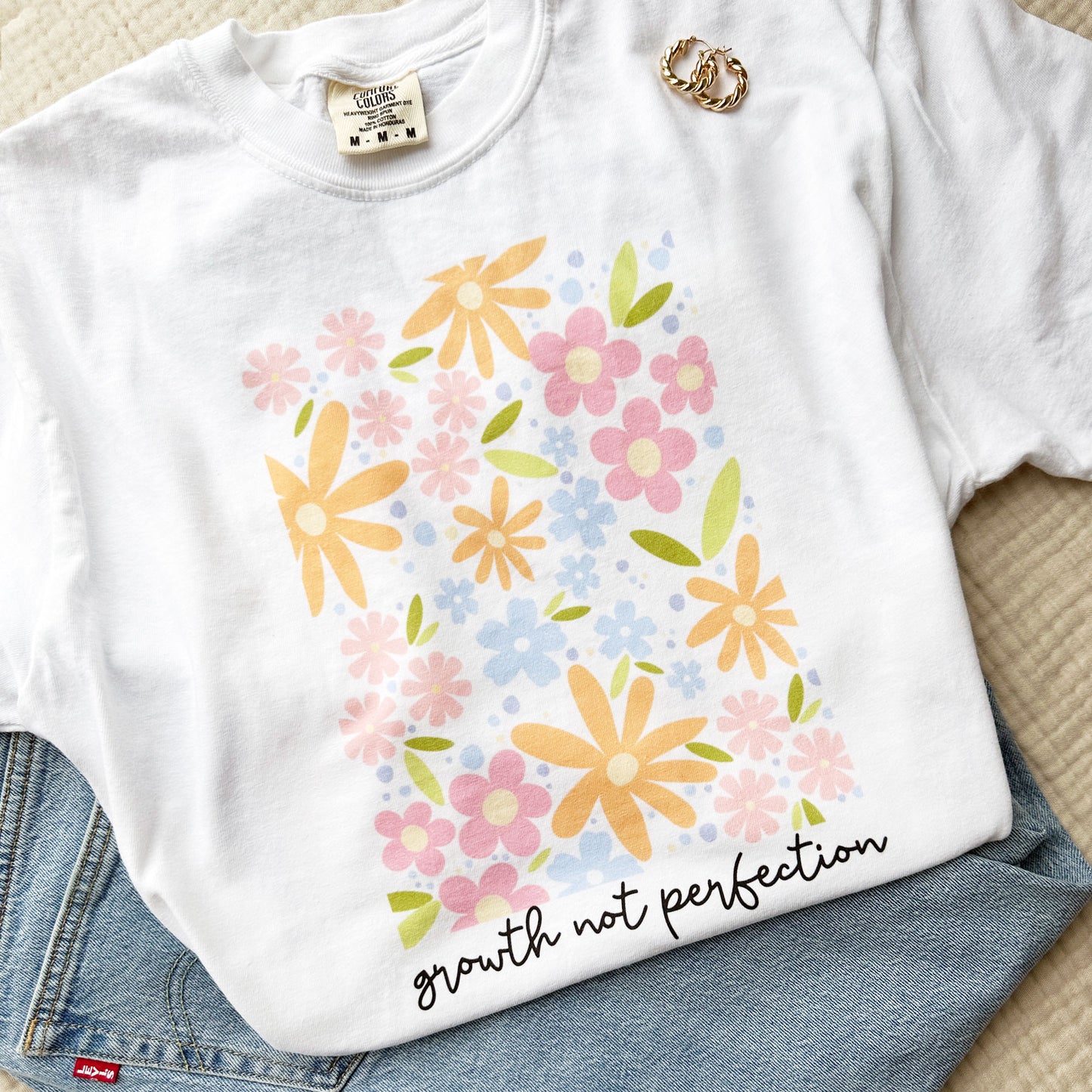 white comfort colors tee with a playful floral print and growth not perfection in a script underneath 