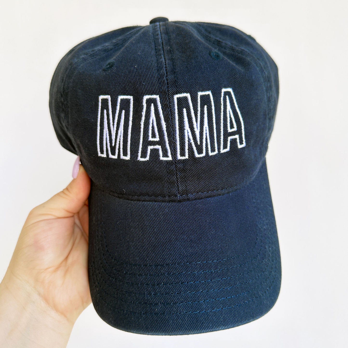 Cute navy baseball hat with mama embroidered across the front in an open block font
