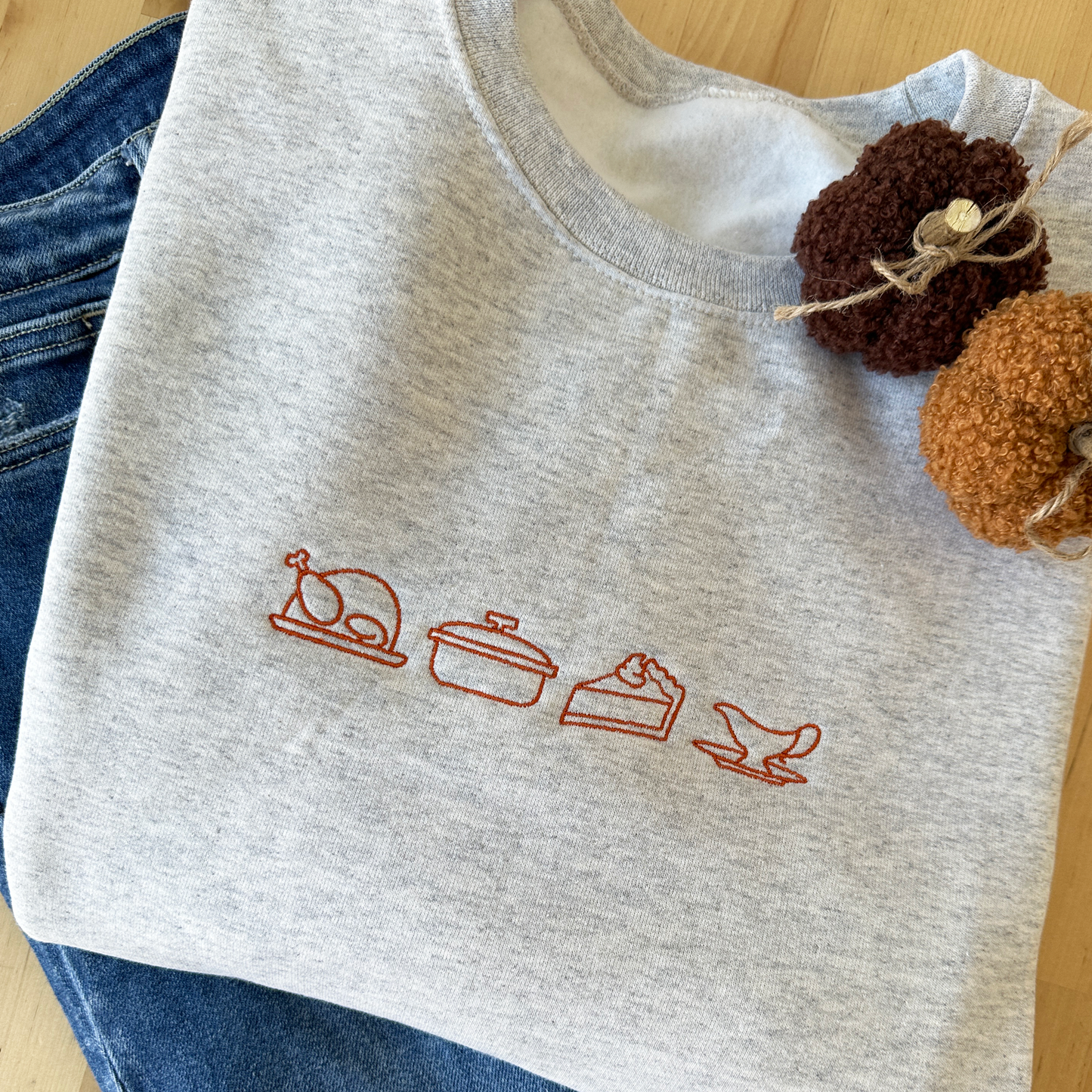 heather oat crewneck sweatshirt with festive thanksgiving themed outlined icons embroidered across the chest