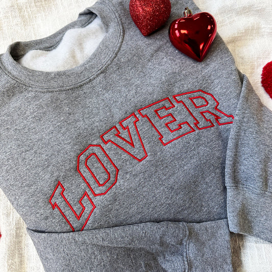 close up image of a valentine's lover embroidered design on the font of a gray crewneck sweatshirt