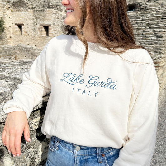 Close up of am embroidered sweet cream crewneck sweatshirt with lake garda italy embroider design