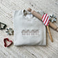 cookie cutters surrounding a crewneck sweatshirt with gingerbread men embroidered across the chest