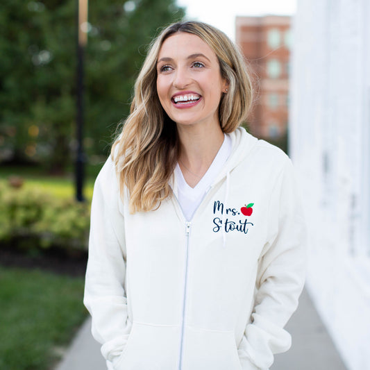 girl wearing a white full zip jacket with custom name and mini apple embroidery